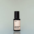 A bottle of Desert Road Eau de Parfum against a grey background.