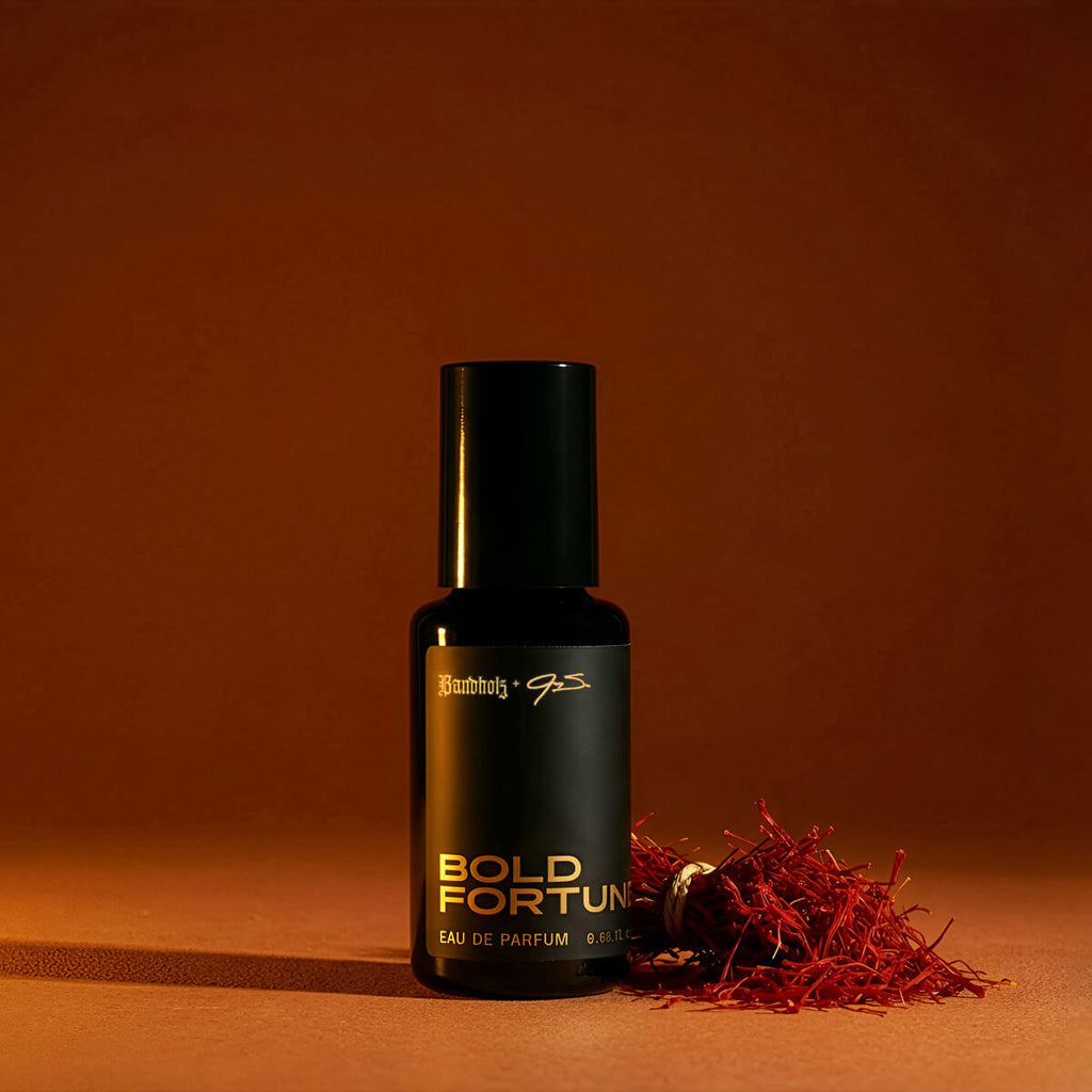 Bandholz Bold Fortune Eau de Parfum bottle with saffron threads on a warm orange background representing the fragrance’s rich spice notes.