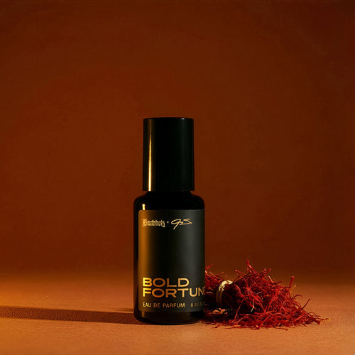 Bandholz Bold Fortune Eau de Parfum bottle with saffron threads on a warm orange background representing the fragrance’s rich spice notes.