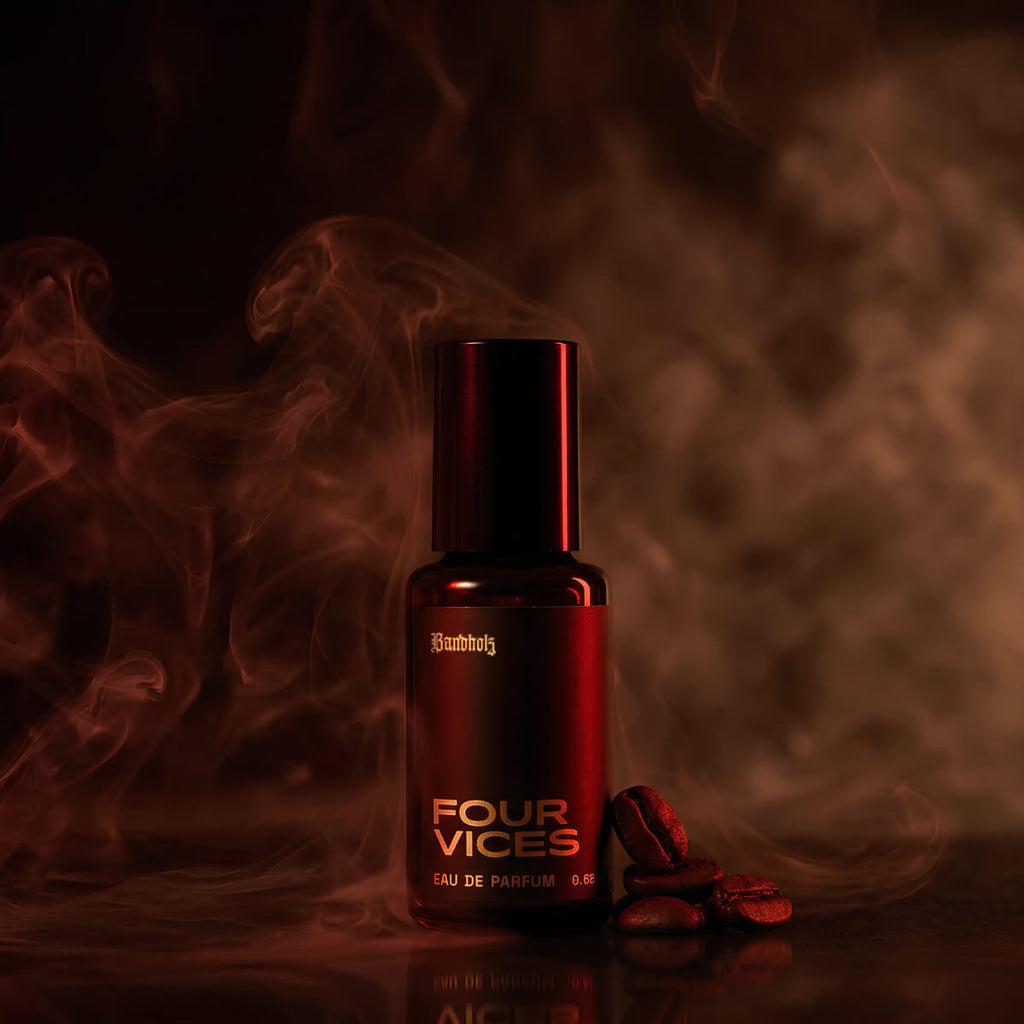 Four Vices Eau de Parfum bottle by Bandholz surrounded by swirling smoke and coffee beans on a dark red background. Image evokes a rich, smoky fragrance with notes of coffee, tobacco, spice, and agarwood.