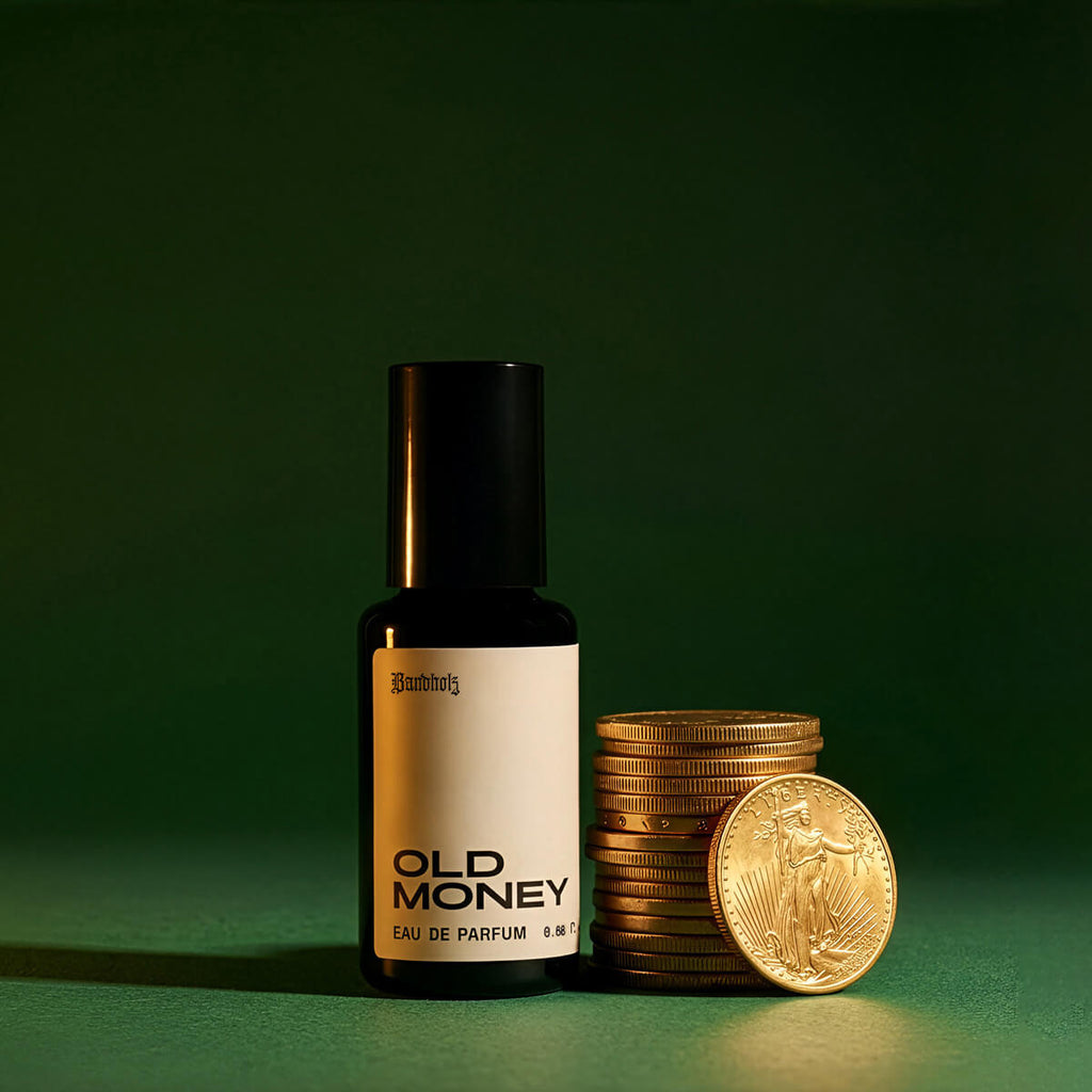 Bandholz Old Money Eau de Parfum bottle beside stacked gold coins on a green background symbolizing the fragrance’s classic refined character.