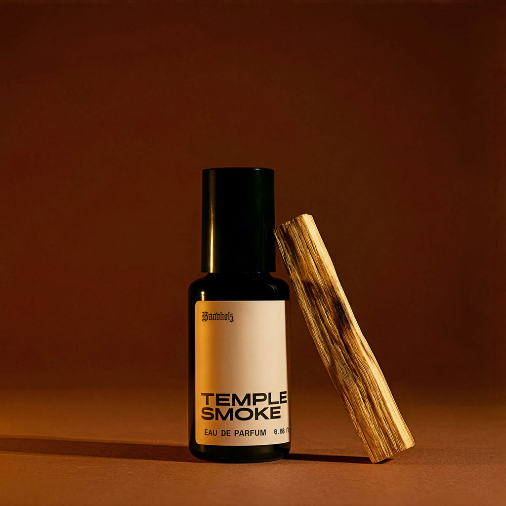 Bandholz Temple Smoke Eau de Parfum bottle with palo santo wood on a warm brown background highlighting the fragrance’s smoky wood scent.